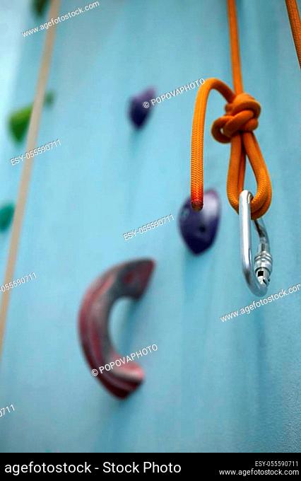 Carabiner with climbing rope on climbing wall background, a vertical picture