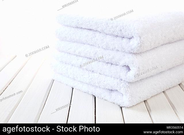 Stack of three white fluffy bath towels on the background of white boards