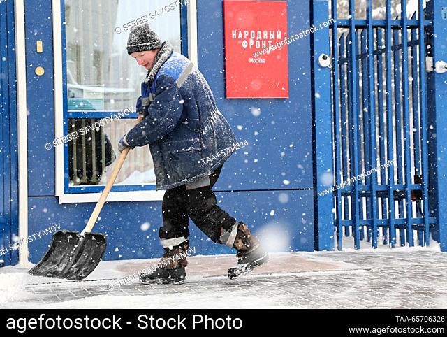 RUSSIA, MOSCOW - DECEMBER 13, 2023: A utility worker shovels snow outside the All-Russia People's Front call centre ahead of President Putin's annual special...