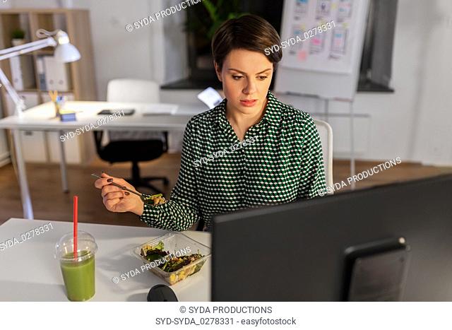businesswoman eating and working at night office