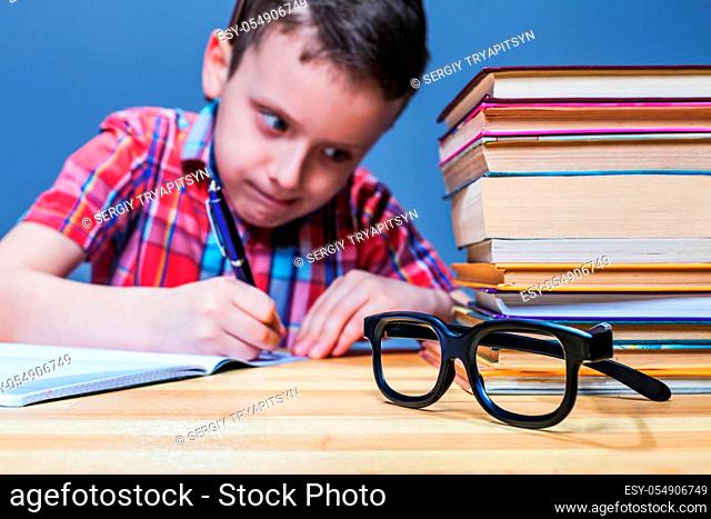 Pensive schoolboy study at school, homework learning. Pupil in glasses against books