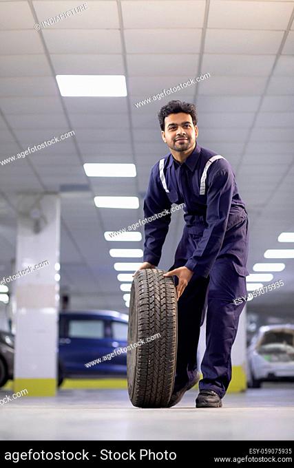 Technician rolling a new tyre in a workshop, during repairs