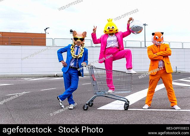 Funny characters wearing animal masks and colored business suits having fun on empty parking lot