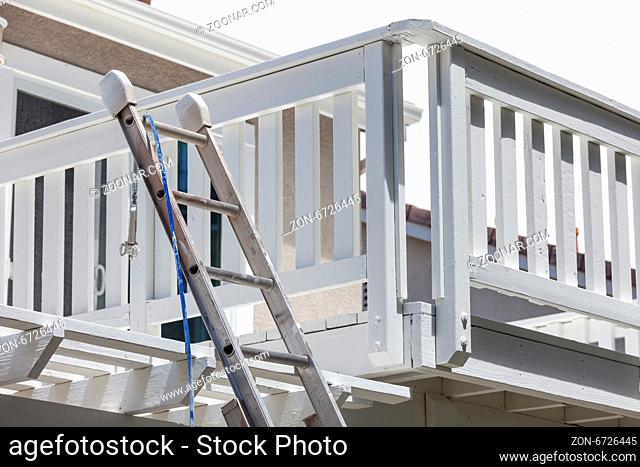 Construction Ladder and Painting Hose Leaning on White House Deck