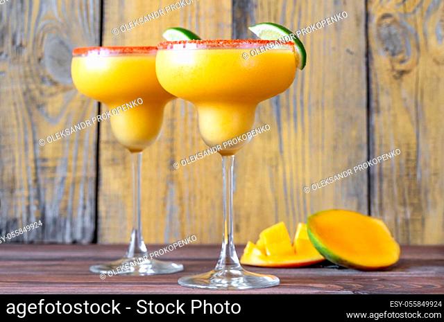 Glasses of Frozen Mango Margarita cocktails garnished with paprika salt rim