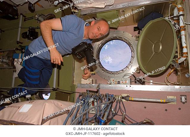 Astronaut Jeffrey N. Williams, Expedition 13 NASA space station science officer and flight engineer, holds a camera prior to photographing the topography of a...