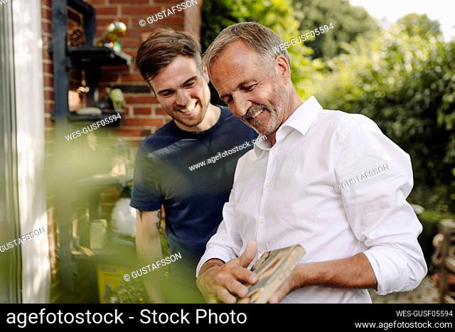 Father showing mosaic tile to son while standing outdoors