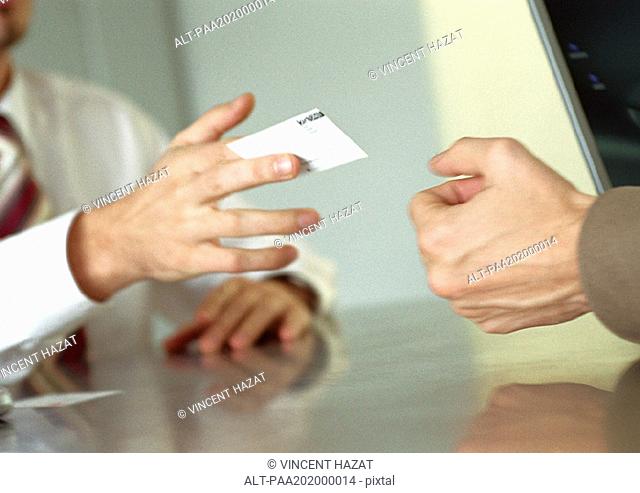 Businessman handing business card to man