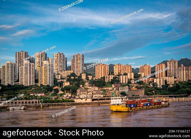 Chongqing, China - August 2019 : Huge cargo ship transporting large shipping containers departing port in Chongqing city