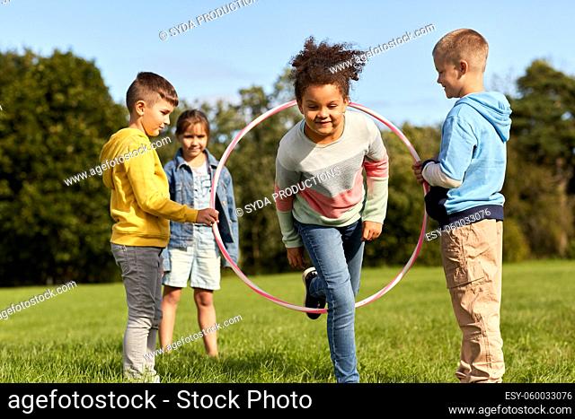 happy children playing game with hula hoop at park