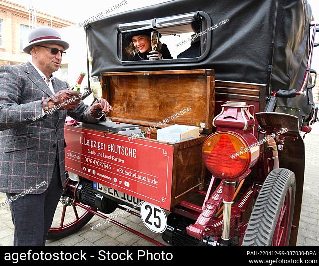 PRODUCTION - 03 April 2022, Saxony, Leipzig: Former car manager Joe Laube welcomes his guests in his historic-looking 1st Leipzig e-carriage with a glass of...