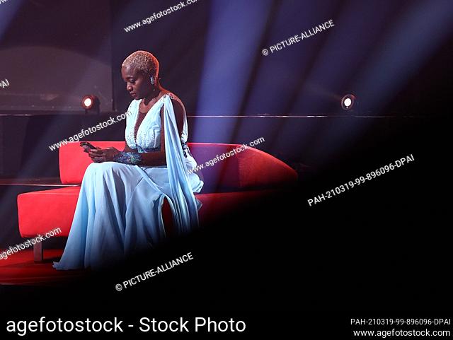 19 March 2021, North Rhine-Westphalia, Cologne: Auma Obama, author, sits on a sofa in the third round of the RTL dance show ""Let's Dance"" and looks at her...