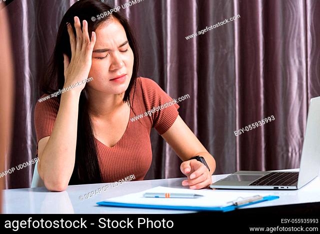 Work from home, Fatigued or strain Asian business young beautiful woman sitting on desk workspace feeling tired stressed hand hold head after long sedentary...