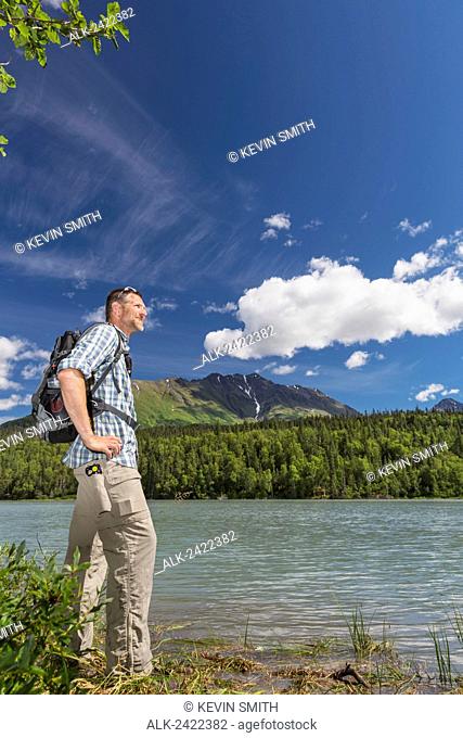 Male hiker taking in the view at a Trail lake with Kenai Mountains in the background, Summer, Moose Pass, Kenai Peninsula, Southcentral Alaska, USA