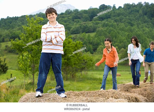 woman and a man standing with their children on hay bales