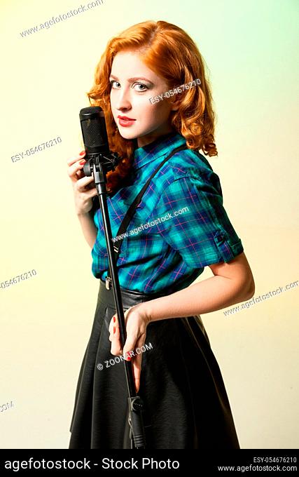 Portrait of attractive singer with red hair singing in mic.Studio shot