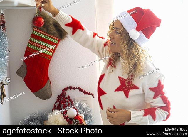 Pretty adult woman in home decoration activity for christmas time and new year eve festivity holidays - happy people enjoy december event - curly lady with red...