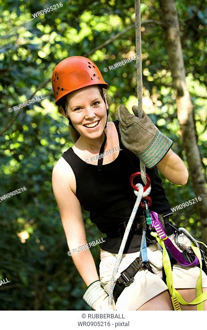 Portrait of a young woman smiling while rappelling
