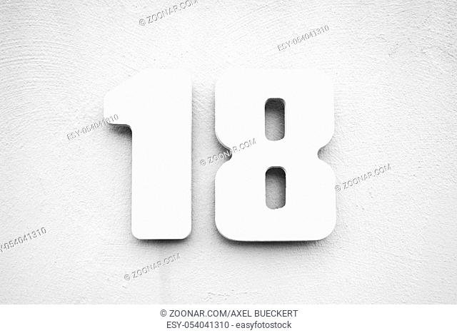 house number 18 on textured wall, white on gray