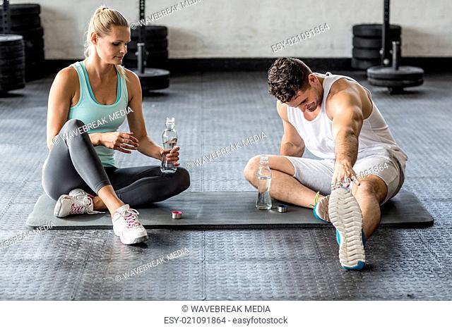 Sports couple stretching and drinking water