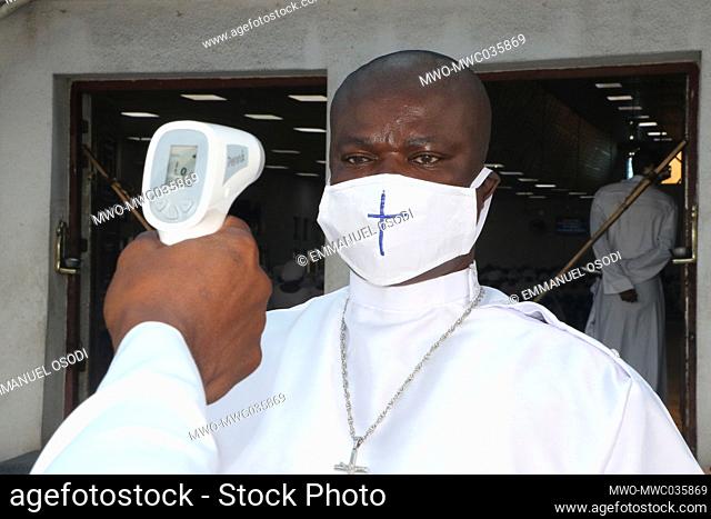 A church official checks the body temperature of a church member to ensure and enforce the coronavirus preventive protocols