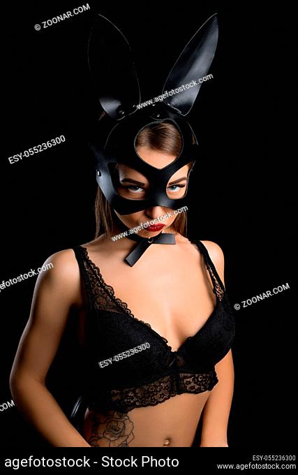 Girl in mask and bunny ears wearing black lace bra cropped portrait in the dark