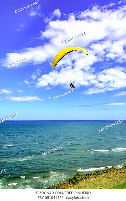 Paraglider flying alone over the beach with blue sky in the background