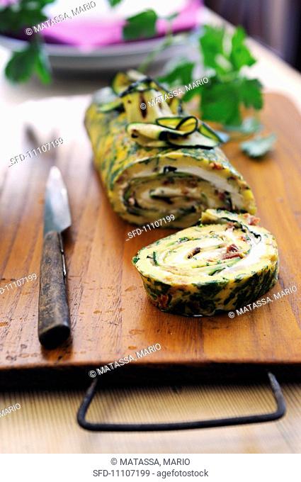 Herb and sun dried tomato omelet roulade filled with ham, cheese and courgette