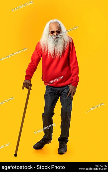 A HAPPY OLD MAN WEARING GOGGLES STANDING AND HOLDING WALKING STICK