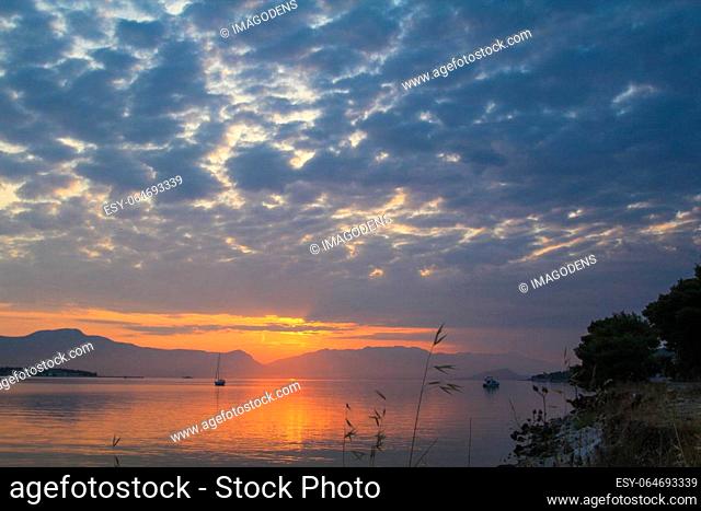 Scenic sunset and a lonely sailboat at the coast of Trogir, Croatia