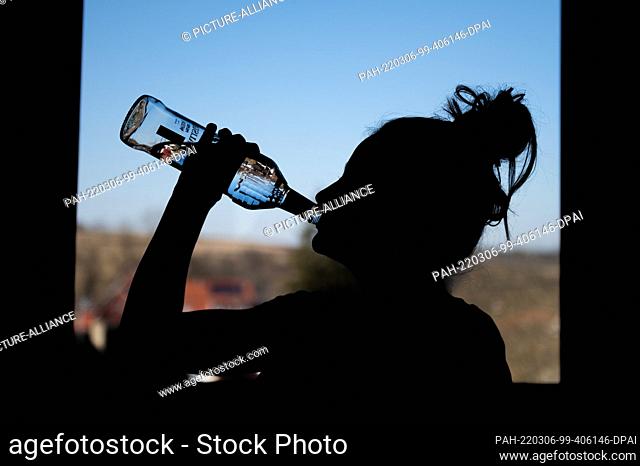 04 March 2022, Baden-Wuerttemberg, Rottweil: Illustration: A teenage girl drinks a bottle of vodka in her room. (To dpa ""DAK: Depressed kids abuse addictive...