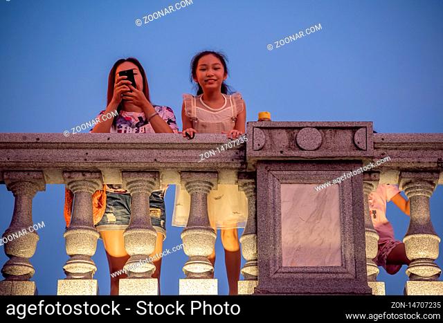 Guilin, China - August 2019 : Mother with her children looking down from the road Bridge over the estuary of Rong and Shan Lakes at night, Guilin town