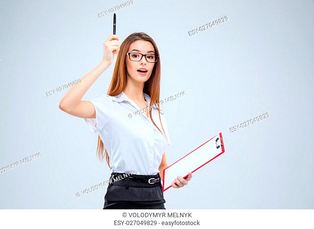 The young business woman in glasses with pen and tablet for notes on a gray background