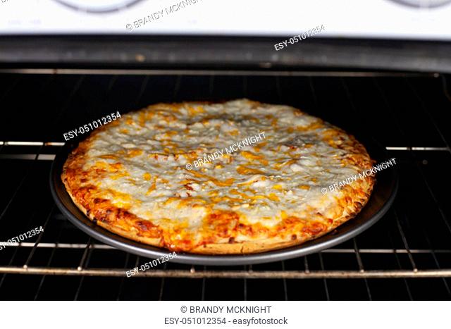 Cooked cheese pizza ready to be pulled out in the oven