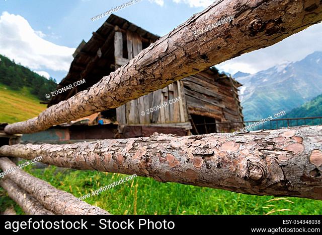 Close-up Wooden vintage fence on the background of an old wooden barn in a mountain Caucasian village