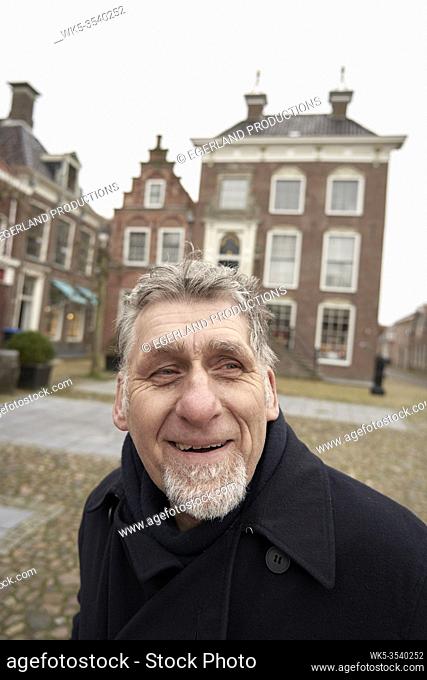 happy Friesian senior man in front of city hall of Workum, Friesland, Netherlands