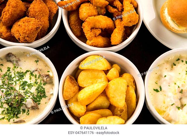 Mixed brazilian snacks, including pastries, fried chicken, salads, soups, fries, kibe
