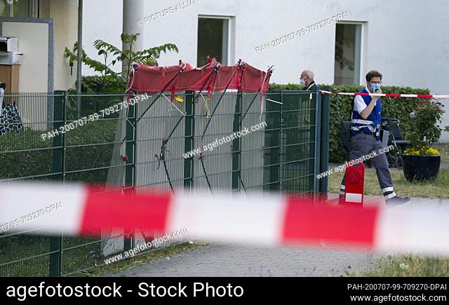07 July 2020, Rhineland-Palatinate, Mainz: A first aider walks past the screened crime scene in the Gonsenheim district, where a man was shot by police