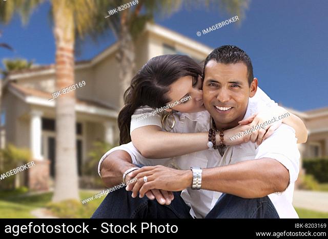 Young happy hispanic young couple in front of their new home