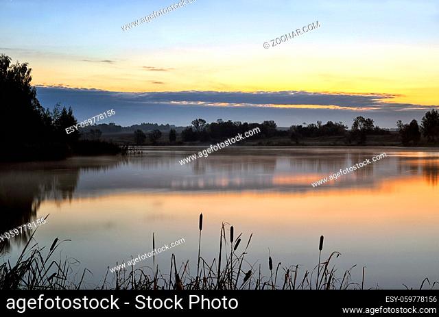 Sunrise landscape with a lake and the mist over the water