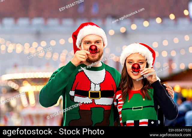 happy couple in christmas sweaters and santa hats
