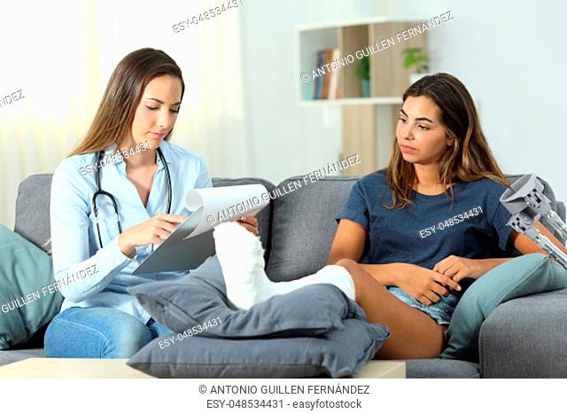 Doctor and patient checking medical history sitting on a couch in the living room at home