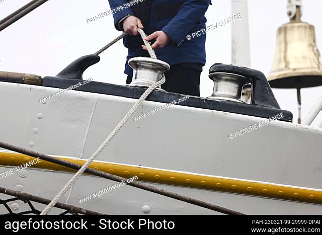 20 March 2023, Schleswig-Holstein, Kiel: A crew member of the ""Gorch Fock"" holds a rope in his hand. After a long winter break