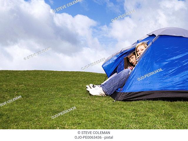 Teenage girls peering out of tent