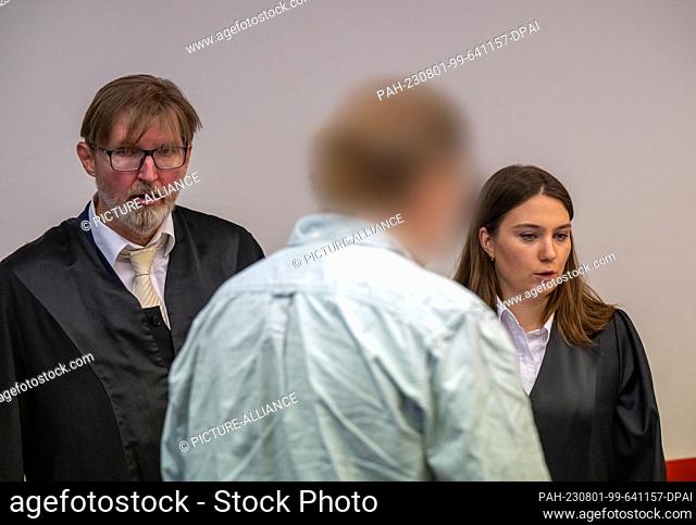 01 August 2023, Bavaria, Munich: The defendant stands in the courtroom in front of his two lawyers. The man allegedly stood idly by while his wife died of...