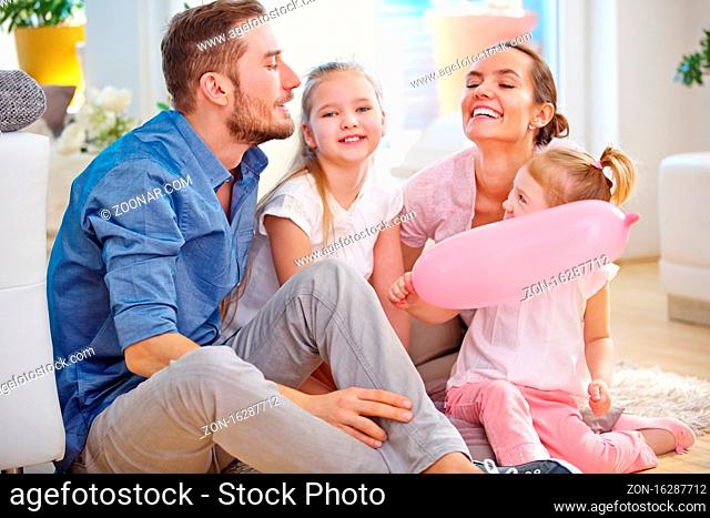 Glückliche Familie mit zwei Kindern sitzt zu Hause im Wohnzimmer und spielt