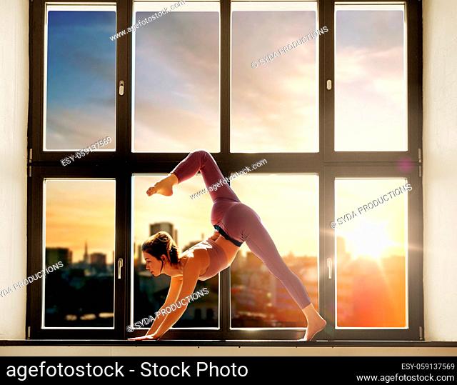 woman doing yoga exercise on window sill at studio