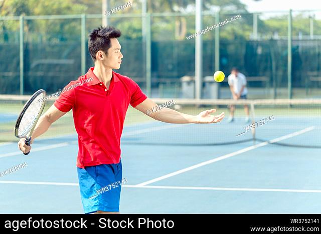 Chinese professional tennis player ready to hit the ball with the racket after tossing while serving in the beginning of a difficult match