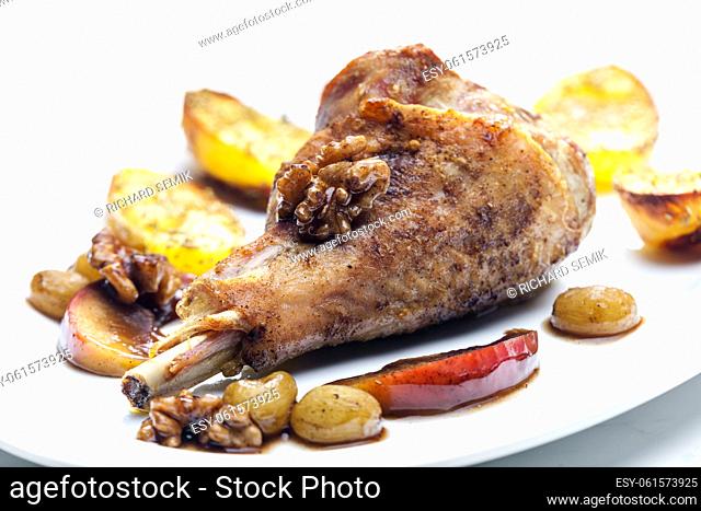 poultry leg baked with fruit and walnuts served with fried potatoes