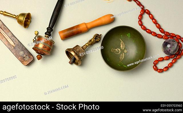 Tibetan singing copper bowl with a wooden clapper on a gray background, objects for meditation and alternative medicine, top view